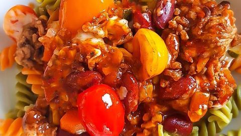 Eine bunte Pasta mit einer herzhaften Bolognese über grünem und orangefarbenem Fusilli. Das Gericht wirkt appetitlich und reichhaltig.