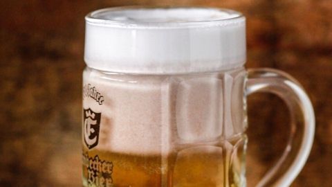 Ein Bierkrug mit schaumiger Guiness-Oberfläche steht auf einer Tischplatte, umgeben von rustikaler Holzdekoration.