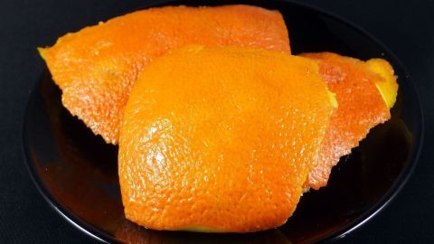 Orangenschalen auskochen und in das Wischwasser geben, durch das Öl aus den Schalen, wird der Boden schön glänzend und streifenfrei. Orangen liegen auf einem schwarzen Teller, glänzend und frisch, bereit zum Verzehr im eleganten Ambiente.