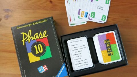 Das Spiel "Phase 10" liegt auf einem Tisch. Die Karten sind verteilt, während die Spieler ihre Züge machen.