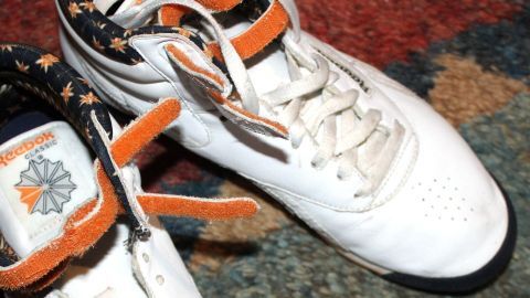 Wenn deine weißen Turnschuhe schmutzig geworden sind, kannst du sie mit Backofenspray ganz einfach wieder schneeweiß bekommen. Dieser Haushaltstipp zeigt dir, wie du deine Sneakers aufpeppen kannst. Weiße Turnschuhe liegen auf einem bunten Teppich, dabei sind sie leicht verschmutzt und bereit zur Reinigung mit Backofenspray.