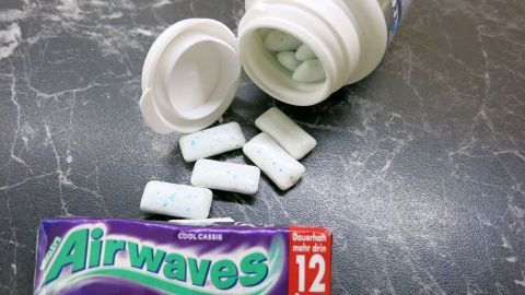Eine geöffnete Airwaves-Packung zeigt weiße Dragees auf einem Marmortisch. Text auf der Packung: "Airwaves Cool Cassis, Dauerhaft mehr drin, 12 Dragees."