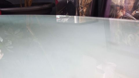 Eine matte Glasoberfläche wird gereinigt, während dekorative Elemente im Hintergrund sichtbar sind.