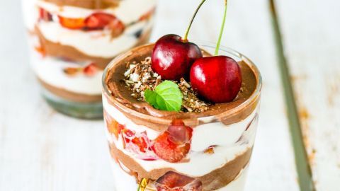 Cremequark wird mit Kirschen geschichtet und in Gläsern serviert, dekoriert mit frischen Kirschen und Minze.