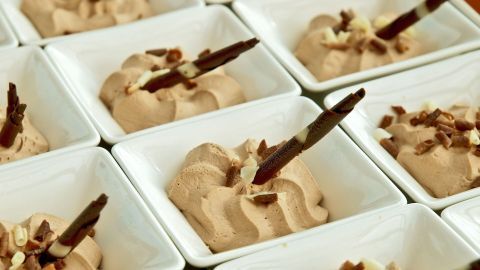Zarte Lebkuchen-Mousse in kleinen Schalen, garniert mit Schokoladensticks und Krokant, ansprechend angerichtet.