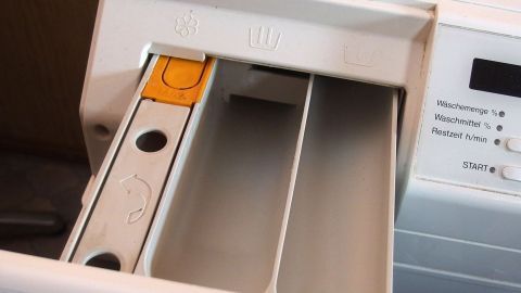 Die Waschmittelschublade ist geöffnet, wobei ein Fach sichtbar ist, das für die Reinigung vorbereitet ist.
