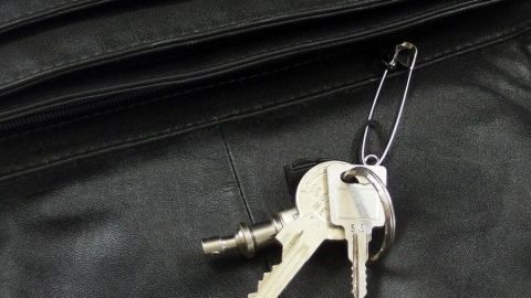 Ein Schlüsselbund liegt an einer Schwarzlederoberfläche, bereit zur Verwendung, um das Schlüsselsuchen in der Handtasche zu vermeiden.