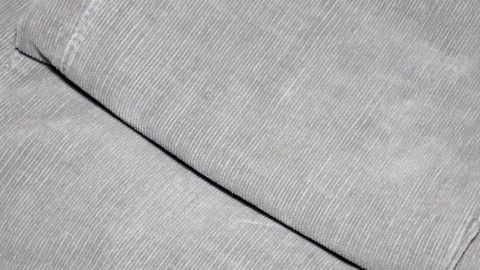 Hässliche flache Stellen auf der Cordhose? Tipp: Mit einem kräftigen Staubsauger daran saugen, die Textilhaare richten sich wieder auf. Grau cordhosen liegen ordentlich gefaltet auf einer Fläche, bereit zum Auffrischen oder zur Verwendung.