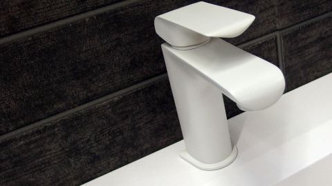 Verdreckte Waschbeckenarmatur mit alter Zahnbürste und Scheuermilch reinigen. Eine moderne Waschbeckenarmatur steht auf einem weißen Waschbecken und ist bereit für die Reinigung mit einer Zahnbürste.