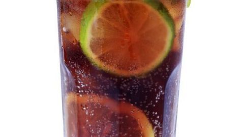 Ein Cocktail mit eisgekühltem Getränk, Zitrone und Minze in einem Glas, das frischen Genuss auf einer sonnigen Veranda vermittelt.