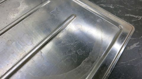 Eine glänzende Edelstahlspüle wird mit einem Lackreiniger für Autos poliert, um ihre Oberfläche zu erneuern.