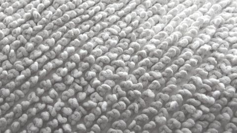 Ein grauer Teppich zeigt eine weiche Textur, auf welcher möglicherweise Haustierflecken entfernt werden müssen.