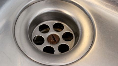Ein Abfluss im Waschbecken ist sichtbar, das Wasser fließt ungehindert durch die Löcher im Abflussgitter.