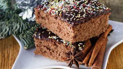 Ein saftiger Gewürzkuchen liegt auf einem weißen Teller, garniert mit bunten Streuseln und einer zimtigen Dekoration.