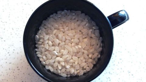 Milchreiskörner können anstatt herkömmlichen Mehl als Soßenbinder verwendet werden - besonders geeignet für Allergiker. Eine schwarze Tasse enthält weißen, körnigen Soßenbinder für Allergiker auf einer hellen Arbeitsfläche.