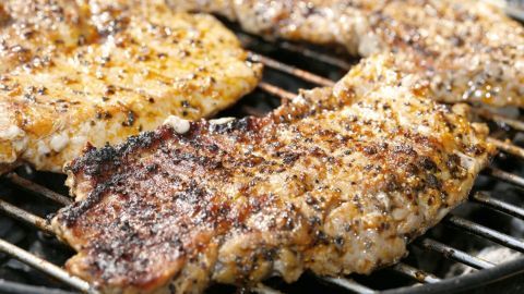 Grillfleisch liegt auf dem Rost und brutzelt, umgeben von Hitze und rauchigen Aromen des Grillens.
