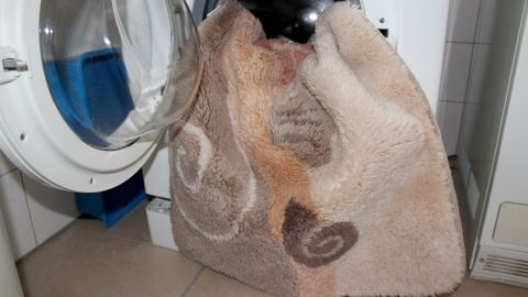 In der Waschküche steht eine Waschmaschine mit einer nassen Decke, die gerade zum Abpumpen bereit ist.