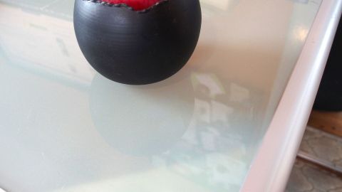Ein schwarzes, rundes Gefäß steht auf einem gläsernen Tisch und bildet keine Staubbildung, während es ansprechend dekoriert ist.
