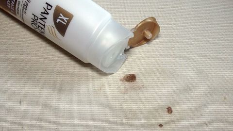 Ein Shampoo-Tube liegt auf einem hellen Stoff und hat einen Blutfleck daneben, während etwas Shampoo darauf gedrückt wird.
