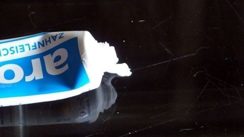 Eine Tube Zahnpasta liegt auf einem Glastisch und wird verwendet, um Kratzer zu entfernen.