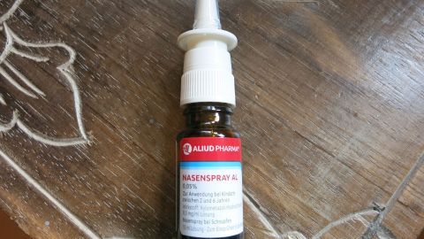 Eine Flasche Nasentropfen aus Kochsalz steht auf einem hölzernen Tisch. Die Tropfen sind bereit zur Anwendung.