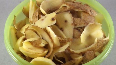 Fenster vom Kachelofen kann man sehr einfach reinigen mit getrockneten Kartoffelschalen. In einer grünen Schüssel liegen Kartoffelschalen, die zur Reinigung von Kachelofen-Fenstern verwendet werden.
