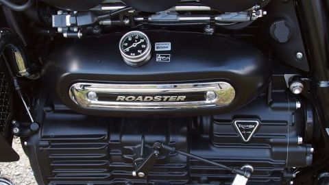 Ein Motor mit einem glänzenden Gehäuse steht zentral, während er Teil eines Motorrads in einer klaren Umgebung ist.