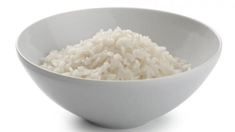 Ein Schüssel voller gekochtem Reis steht auf einem weißen Hintergrund, bereit zum Servieren oder für eine Mahlzeit.