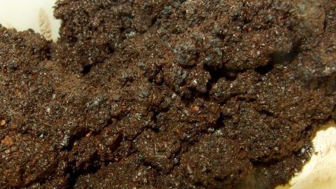 Kaffeegeruch kann auch ohne vollen Vorratsschrank wirken: Kaffeesatz eignet sich perfekt als natürlicher Duftstoff im Schrank. Streue ihn auf ein kleines Schälchen, um den frischen Kaffeeduft zu genießen. Kaffeepulver liegt locker verstreut auf einer Oberfläche und füllt den Raum voller Kaffeearoma. Keine Textbeschriftung vorhanden.