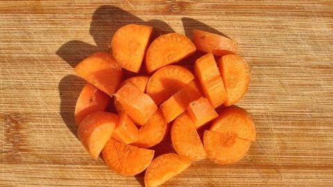 Karottenwürfel liegen auf einem Holzbrett und wirken frisch und appetitlich in der Küche.