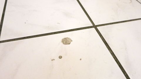Ein Fleck auf einem hellen Fliesenboden, der gereinigt werden muss, um Edelstahl-Reiniger zu verwenden.