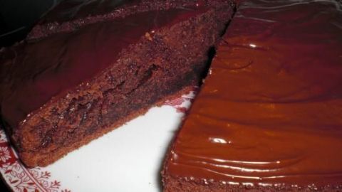 Ein Stück Schokokuchen wird angeschnitten, ruht auf einem dekorativen Teller in einer Küche. Keine zusätzlichen Textelemente.