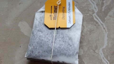 Keine hässlichen Streifen und Schlieren mit schwarzem Tee. Ein Teebeutel liegt auf einer glatten Oberfläche und könnte zur Reinigung von verschmierten Fenstern verwendet werden.