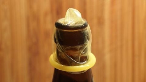 Eine Bierflasche steht aufrecht mit einem transparenten Schutz über dem Flaschenhals, um den Inhalt frisch zu halten.
