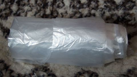 Eine Rolle Müllbeutel im Auto etc. als Einkaufstüten-Ersatz. Ein Müllbeutel liegt auf einem Teppich und könnte als Einkaufstüten-Ersatz verwendet werden, um Abfälle zu transportieren.