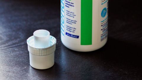 Eine Flasche Meridol Mundspülung steht auf einem Tisch, bereit zur Anwendung gegen Herpes. Der Verschluss liegt daneben.