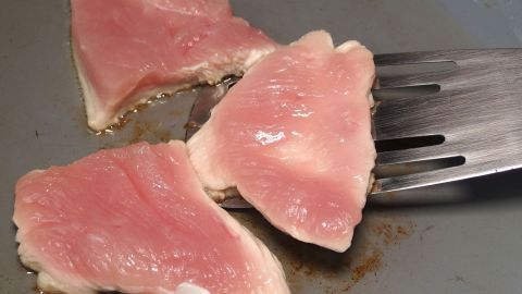 Zum Wenden von Fleisch lieber einen Bratenwender und die (hoffentlich sauberen) Finger nehmen. Dünne Fleischstücke braten in einer Pfanne, während das Fett erhitzt wird und eine goldene Kruste entsteht.