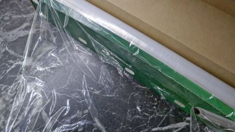 Frischhaltefolie liegt auf einem Wandrollenhalter und klebt frisch in der Verpackung auf einer Oberfläche.
