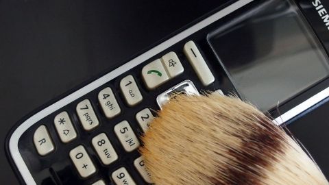 Ein Telefon wird mit einem Pinsel gereinigt, um Staub zu entfernen und es sauber zu halten.