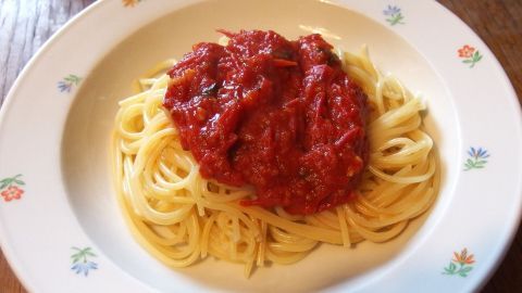 Pasta mit selbstgemachter Tomatensoße aus Dosentomaten liegt appetitlich auf einem bunten Teller.