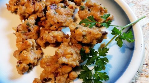 Kichererbsen-Falafel, goldbraun gebraten, liegen auf einem Teller mit frischer Petersilie als Garnitur.
