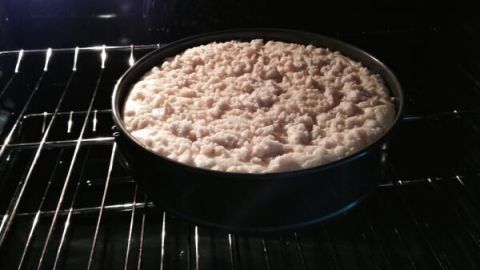 Ein goldbrauner Käsekuchen mit Streuseln backt in einem Ofen, während die Hitze gleichmäßig darauf wirkt.