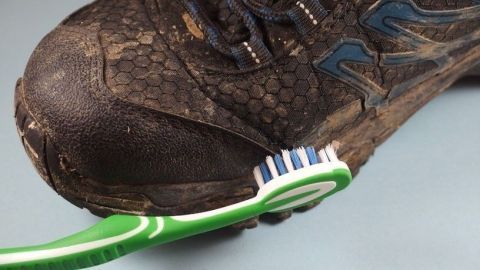 Eine Zahnbürste reinigt den schmutzigen Schuh in einer hellen Umgebung, sodass der Schmutz effektiv entfernt wird.