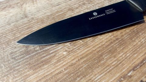 Ein scharfes Küchenmesser liegt auf einem rustikalen Holztisch, bereit zum Schneiden auf einem günstigen Schneidebrett.