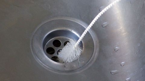 Eine Spritze mit Reinigungsmittel zielt auf den Abfluss, um Verunreinigungen im Küchenbecken zu beseitigen.