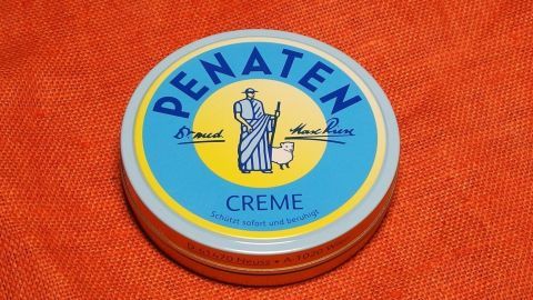 Eine Dose Penatencreme liegt auf einem orangefarbenen Untergrund. Sie ist für die Linderung von Juckreiz bei Hämorrhoiden geeignet.