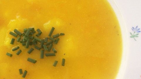 Ein Teller mit schneller Kartoffelsuppe, die golden und cremig aussieht, ist mit frischen Kräutern garniert.