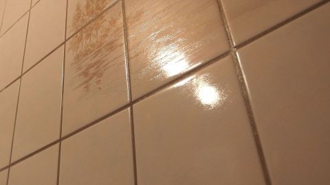Blitzende Fliesen reflektieren Licht, während Klarspüler den Schmutz auf dem Badezimmerfliesen entfernt.