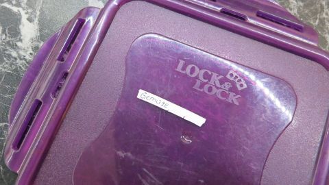 Idealer Tipp zum Beschriften von Tupperware ist Tipp-Ex! Einfach einen Strich auf den Deckel ziehen, und dann mit Kugelschreiber beschriften. Hält super. Ein lila Tupperware-Behälter steht auf einer marmorierten Oberfläche, mit einem Etikett, das den Inhalt beschriftet.