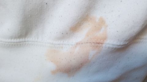 Ein fleckiges weißes Kleidungsstück liegt flach auf einer Oberfläche und zeigt einen braunen Fleck, der entfernt werden soll.